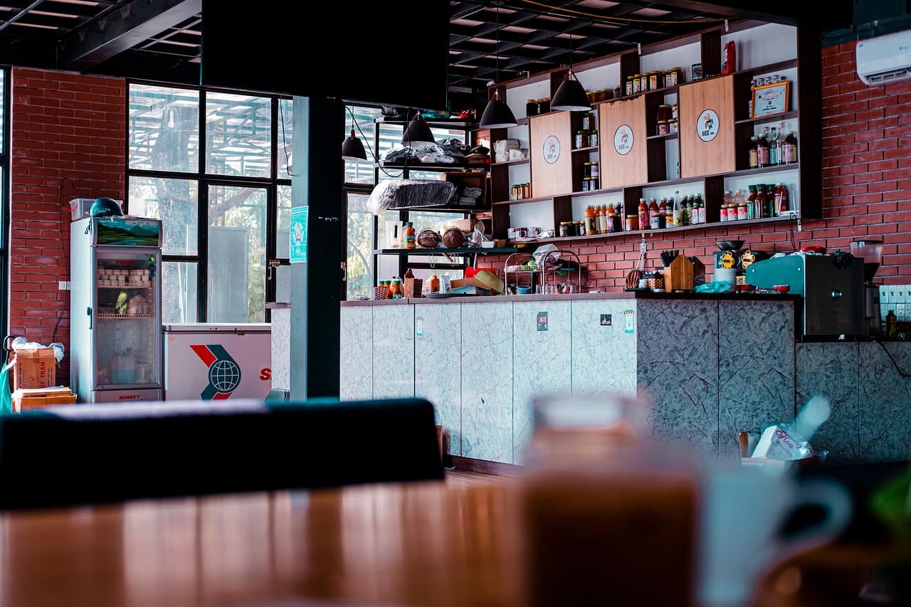 A coffee bar with a long counter, shelves and big windows