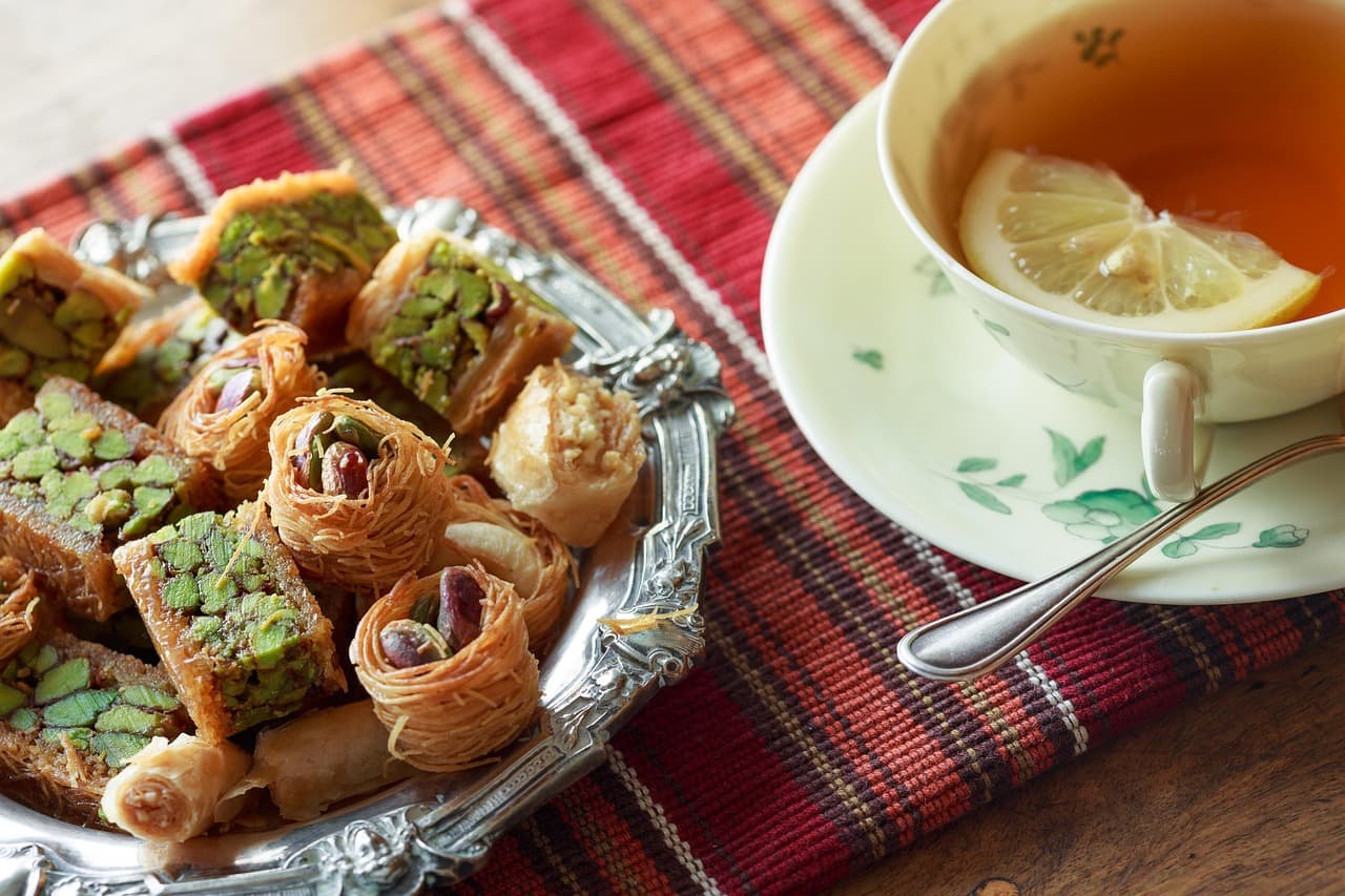 A plate of baklava and pastries with a cup of tea