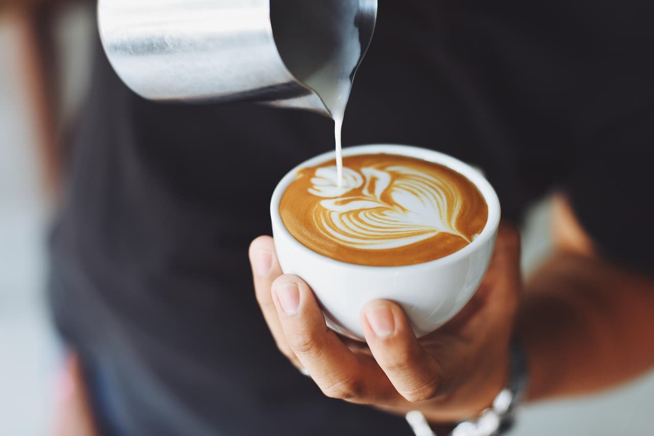 Steamed milk poured into a latte, making a rosetta