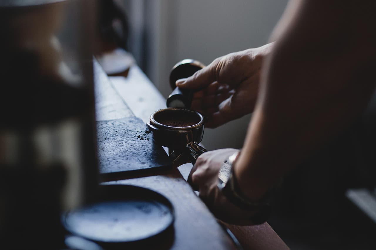 A barista tamping espresso into a portafilter